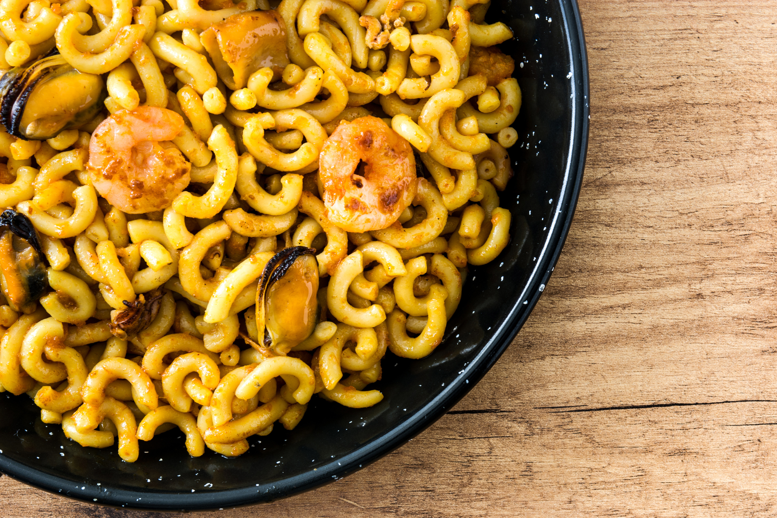 Foto de plato de fideuá sobre mesa de madera